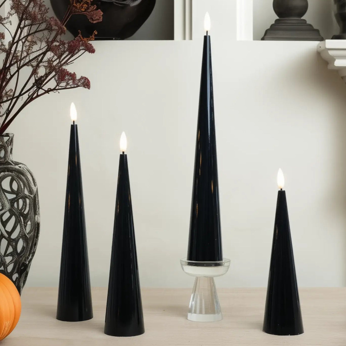 Black cone-shaped candles on a table with decorative elements.