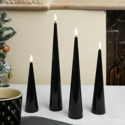 Set of four black cone-shaped candles with lit wicks on a white surface.