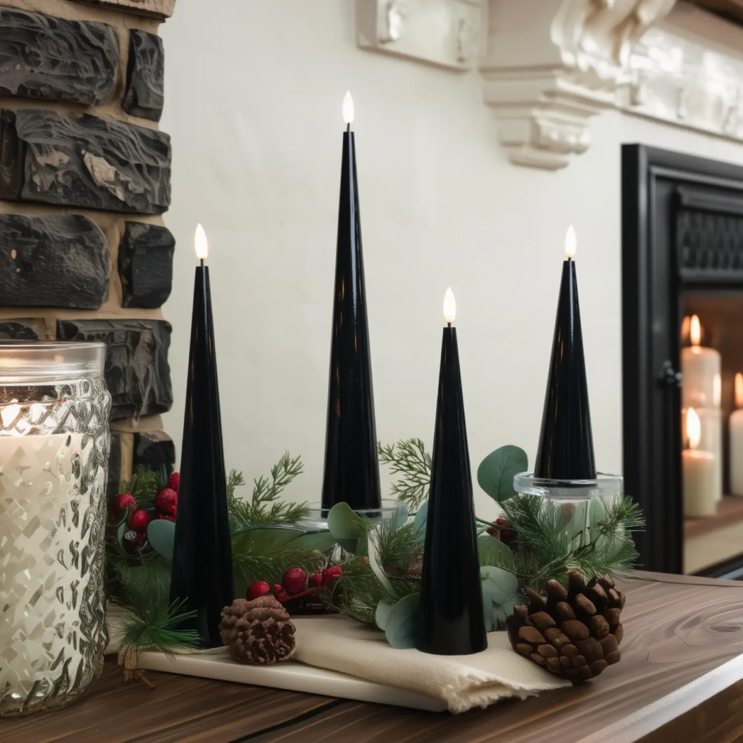 Decorative setup with black candles, greenery, and pinecones on a wooden surface.