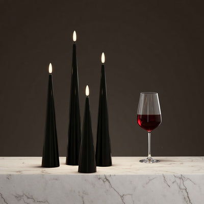Black cone-shaped candles on a table with decorative elements.