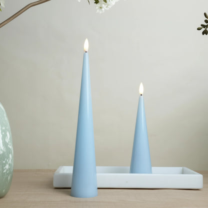 Two light blue cone-shaped candles on a white tray with a neutral background