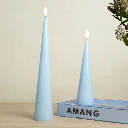 Two lit blue candles on a wooden surface with a 'AMANG' box in the background.