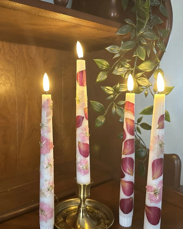Floral-patterned candles on a wooden shelf with a plant in the background