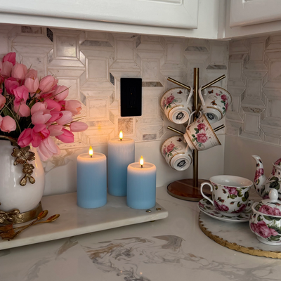 Decorative shelf with candles, flowers, and teacups in a kitchen setting