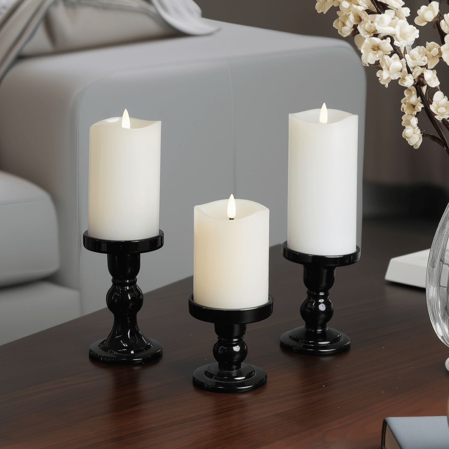 Three lit candles on a table with a book and a cup in a cozy indoor setting.