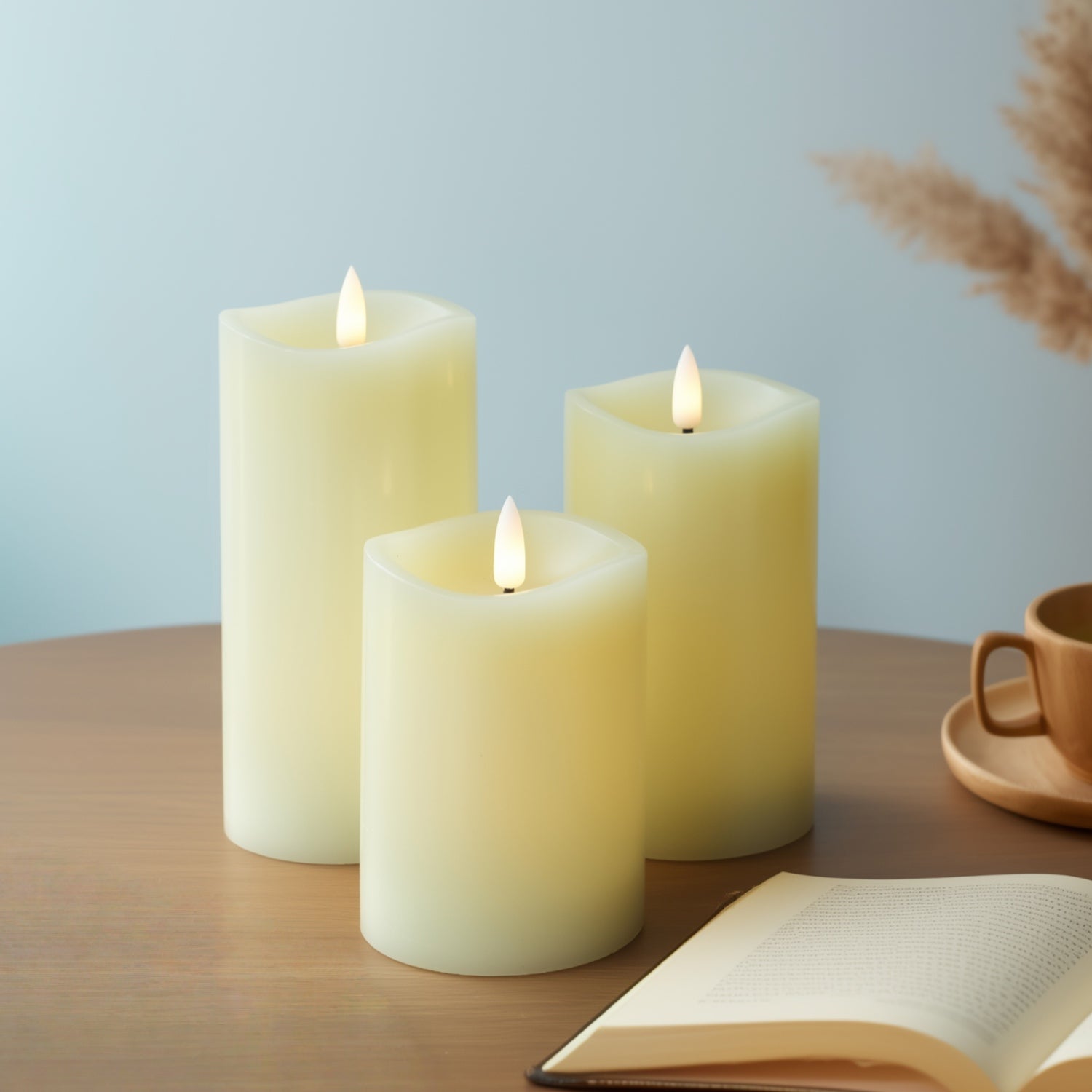 Three lit candles on a wooden surface with a cup and book in the background.#color_ivory