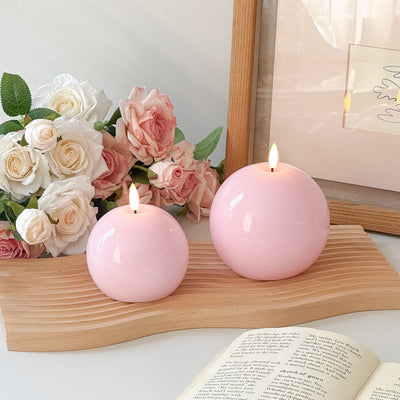 Two pink candles on a stack of books with a plant in the background