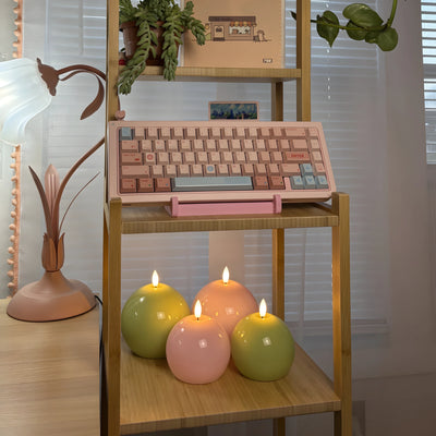 Wooden keyboard on a wooden shelf with lit candles and decorative plants.