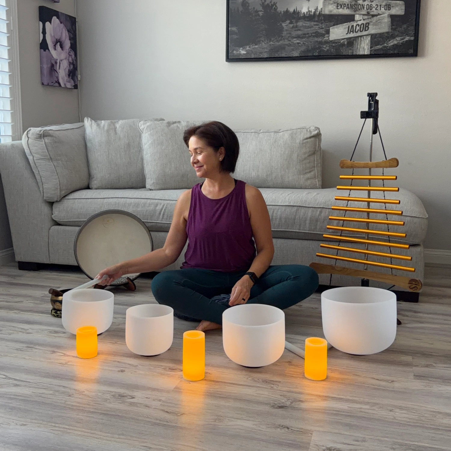 Woman sitting in a living room with white bowls and orange candles on the floor.