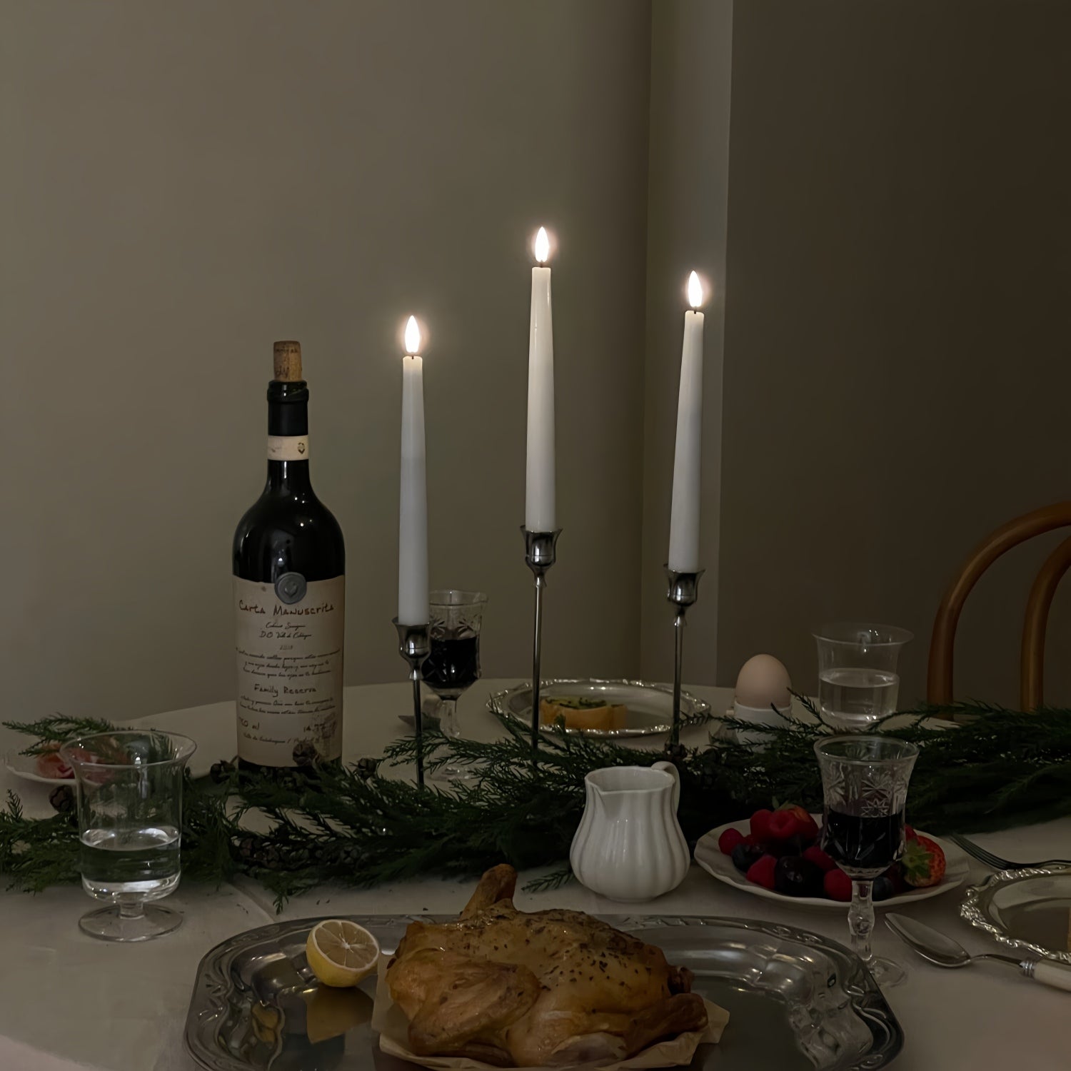 Dining table set with wine, bread, and candles in a cozy setting.