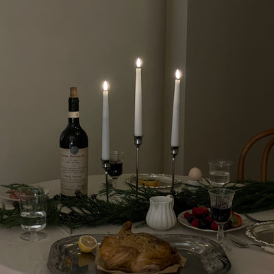 Dining table set with wine, bread, and candles in a cozy setting.