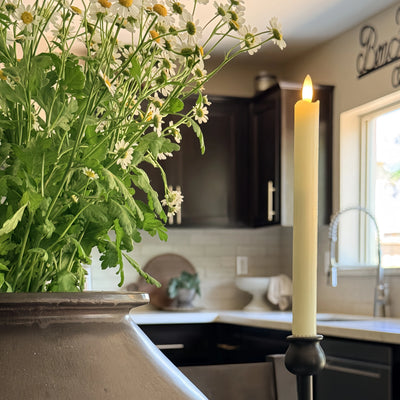 Candle and flowers on a kitchen counter with blurred background