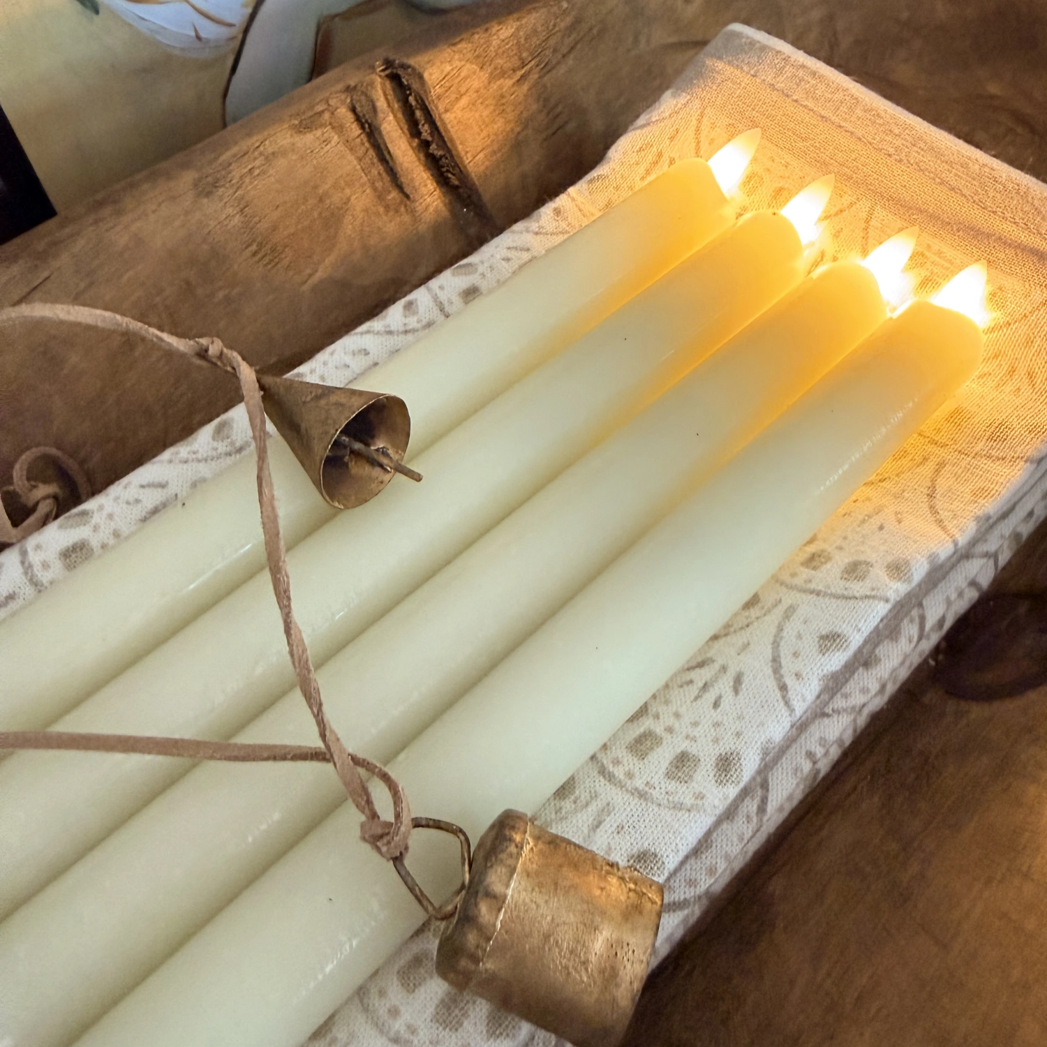 Set of lit candles in a wooden holder with a rustic background