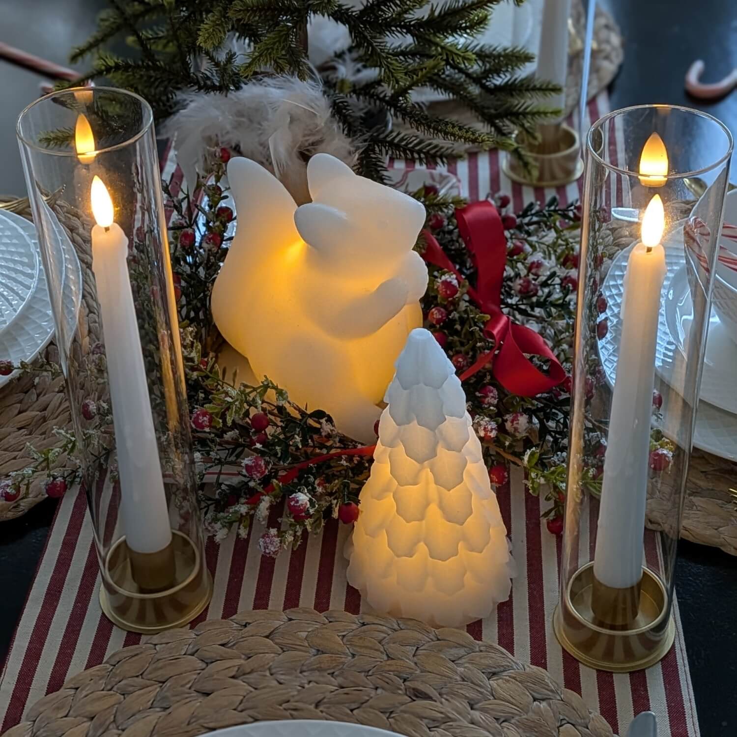 Decorative table setting with candles, a honeycomb-shaped light, and Christmas decorations.
