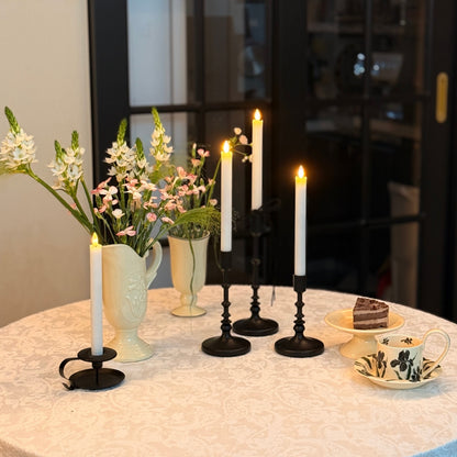 Decorative setup with candles, flowers, and a cake on a table.