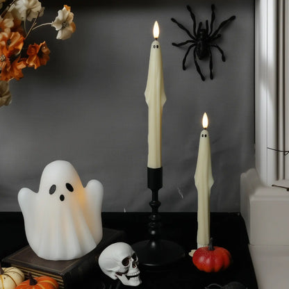 Halloween-themed decor with candles, ghost, spider, and pumpkins on a dark surface.