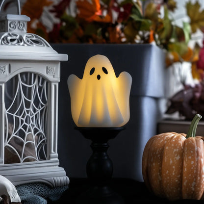 Ghost-shaped light next to a white lantern and pumpkin with autumn decorations.