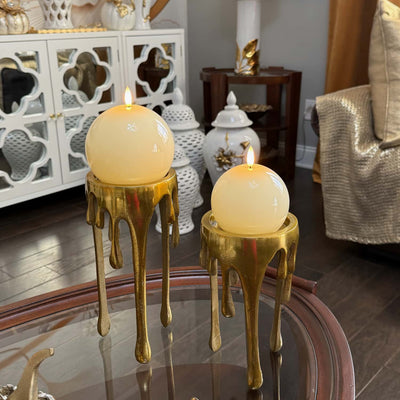 Two gold candle holders with lit candles on a reflective surface in a decorative room.