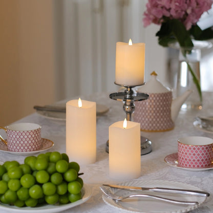Decorative table setting with candles and greenery on a white tablecloth.