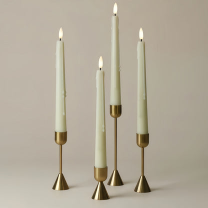 Four candles with brass holders on a neutral background
