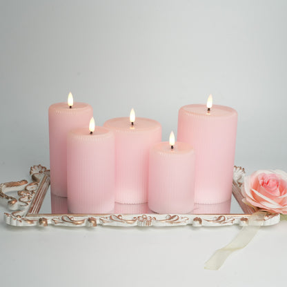 Set of pink candles on a decorative tray with a rose on a light gray background