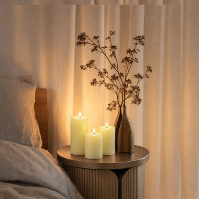 Candlelit scene with candles and a vase on a small table against a curtain backdrop