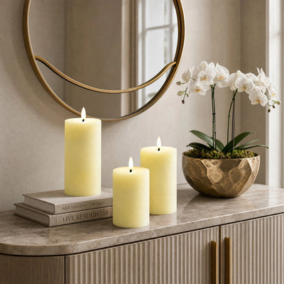 Decorative setup with candles and a plant on a marble surface, featuring a round mirror in the background.