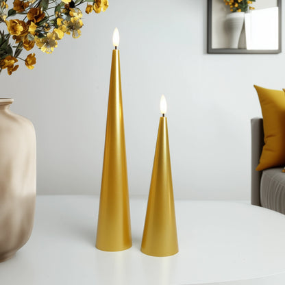 Two gold candles on a white surface with a vase and mirror in the background.