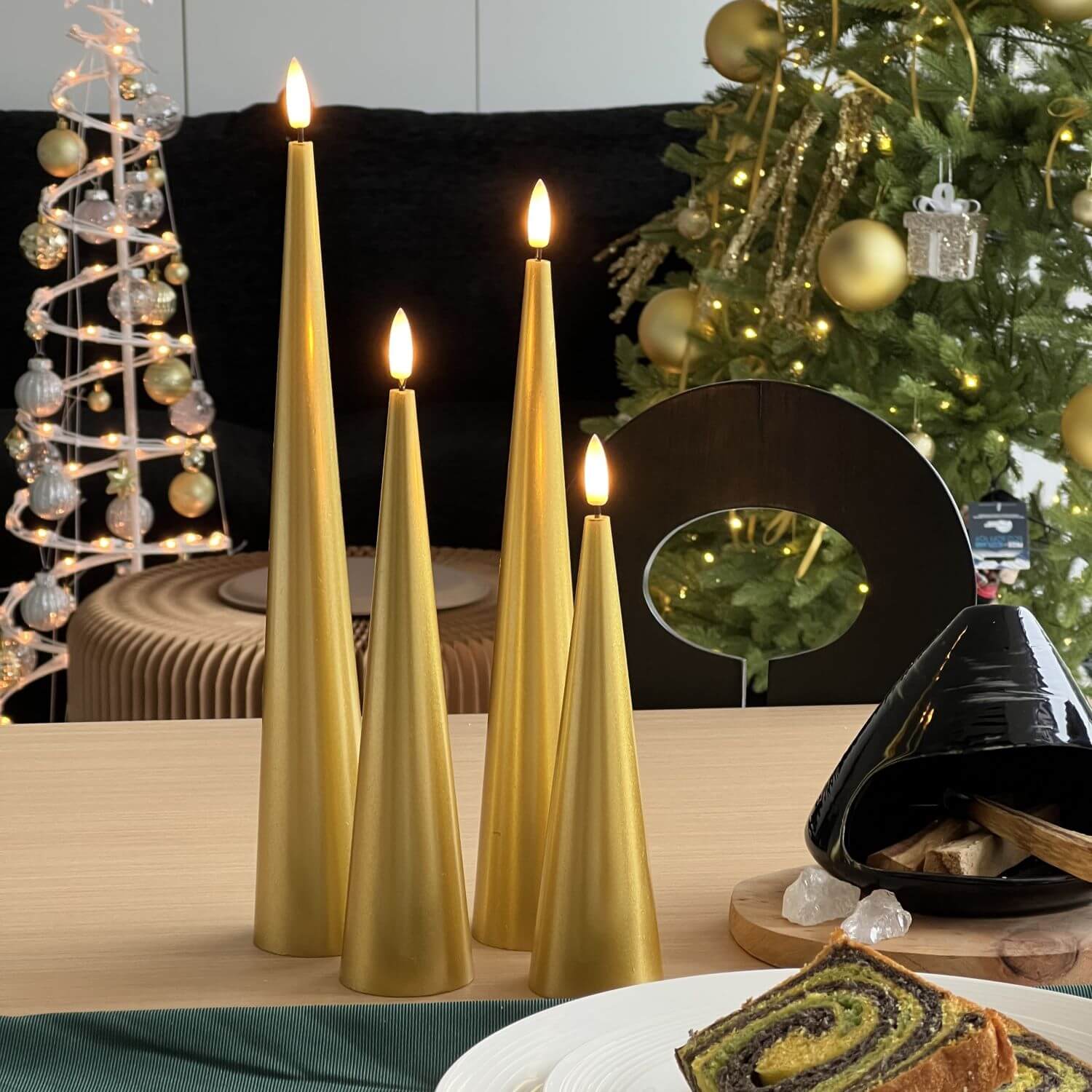 Decorative setup with gold candles, flowers, and greenery on a marble surface.