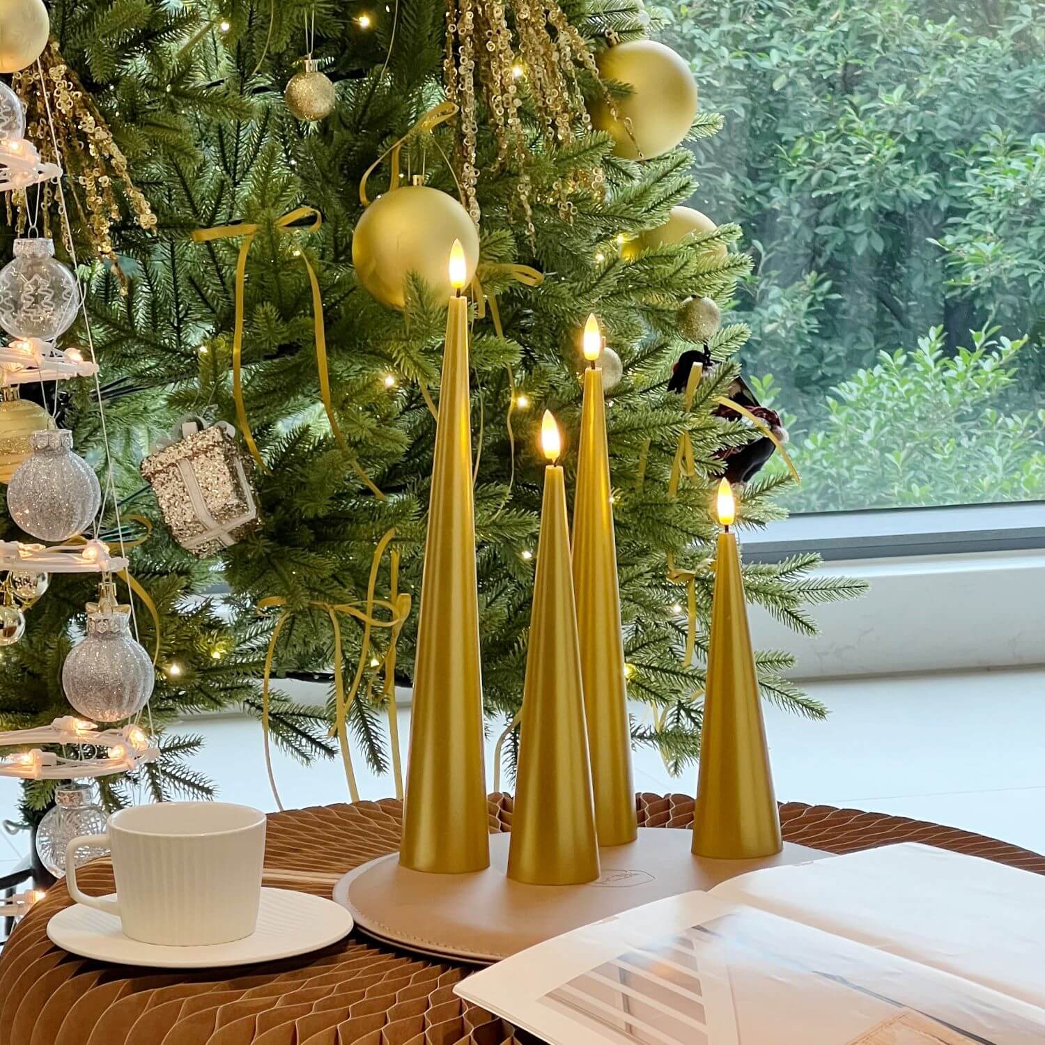 Decorative setup with gold candles, flowers, and greenery on a marble surface.
