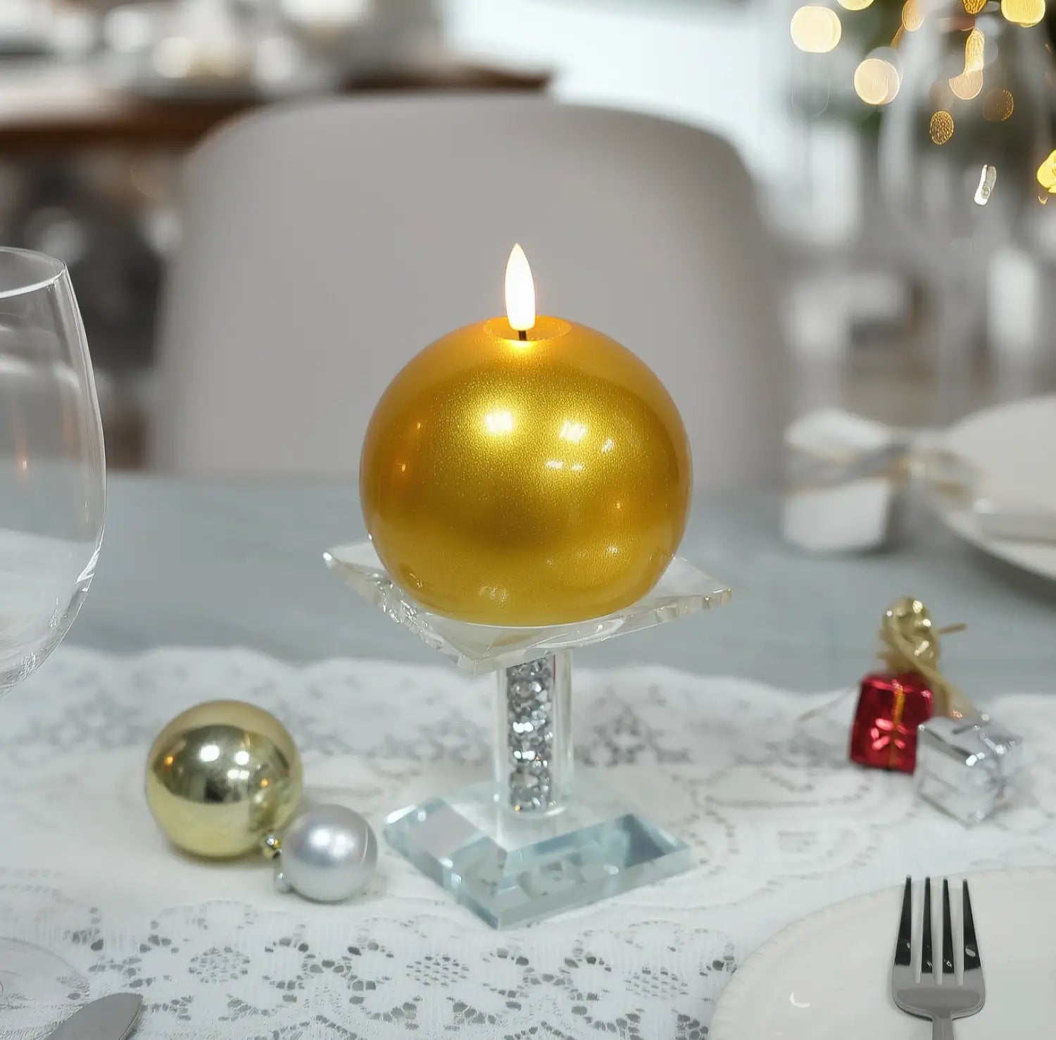Gold candle on a wooden base with Christmas decorations in the background