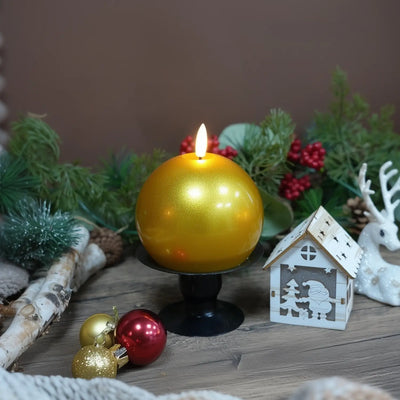 Gold candle on a wooden base with Christmas decorations in the background