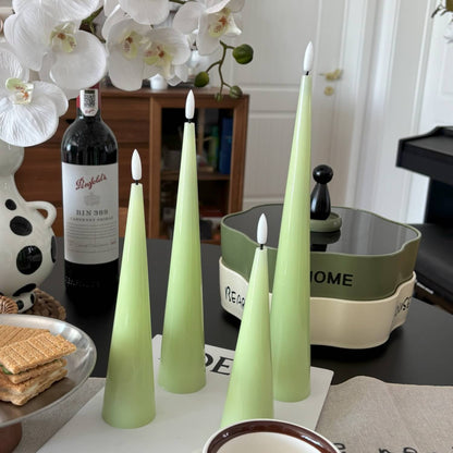Green candles on a table with a bottle of wine and decorative items.