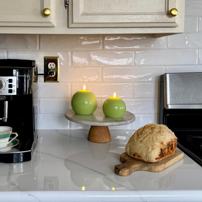 Kitchen counter with coffee maker, loaf of bread, and candles on a cake stand.