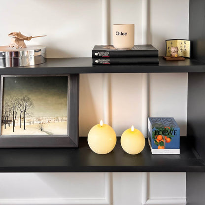 Decorative shelf with candles, books, and a framed picture.