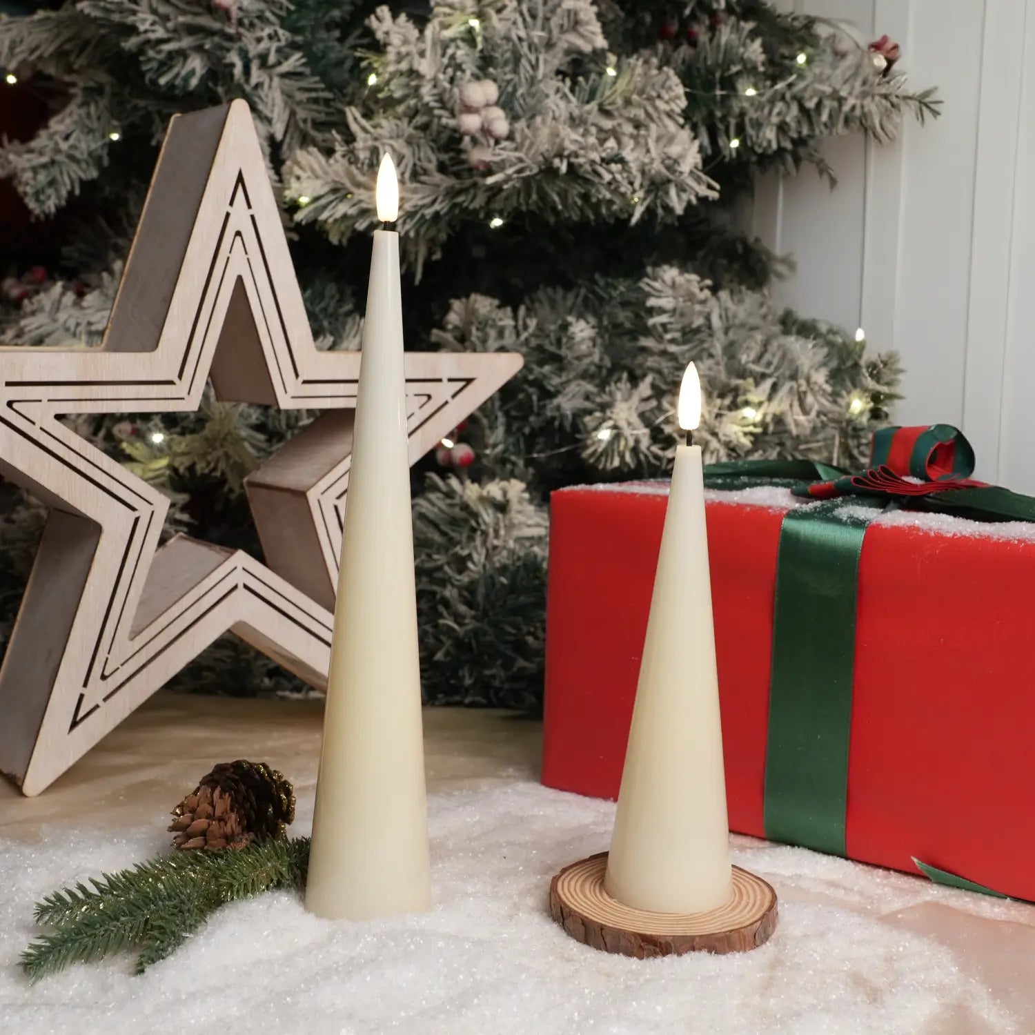 Two white cone-shaped candles with lit wicks on a dark surface with a gray background.