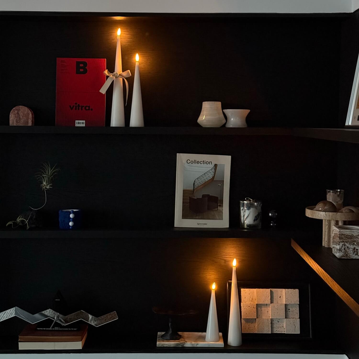 Dark shelving unit with decorative items including candles and a book titled 'Collection'.