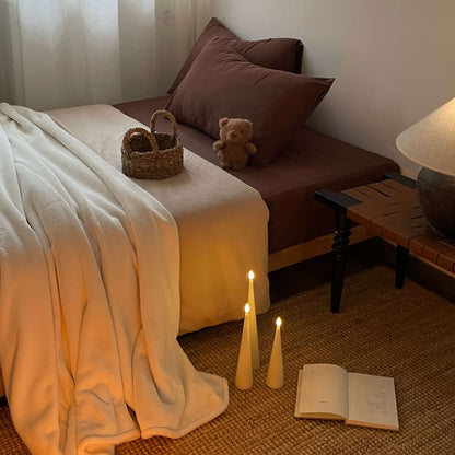 Cozy bedroom scene with a bed, teddy bear, candles, and an open book.
