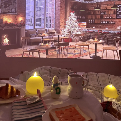 Dining table with food and candles in a cozy indoor setting with a Christmas tree and fireplace.