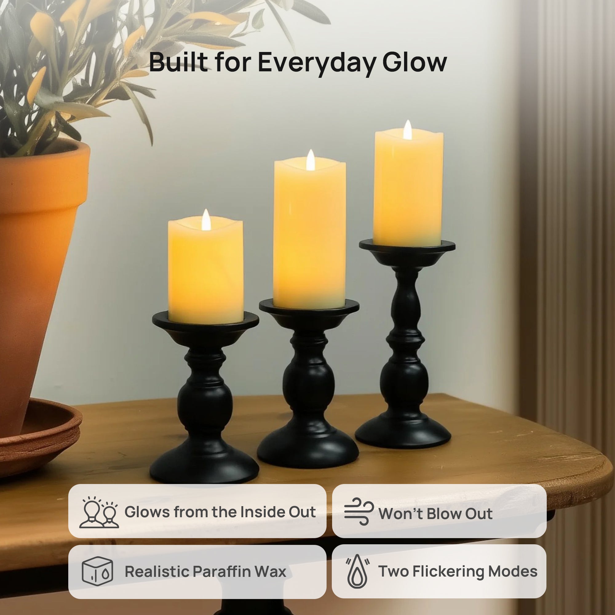 Three candles on black candlesticks with decorative elements on a wooden surface.