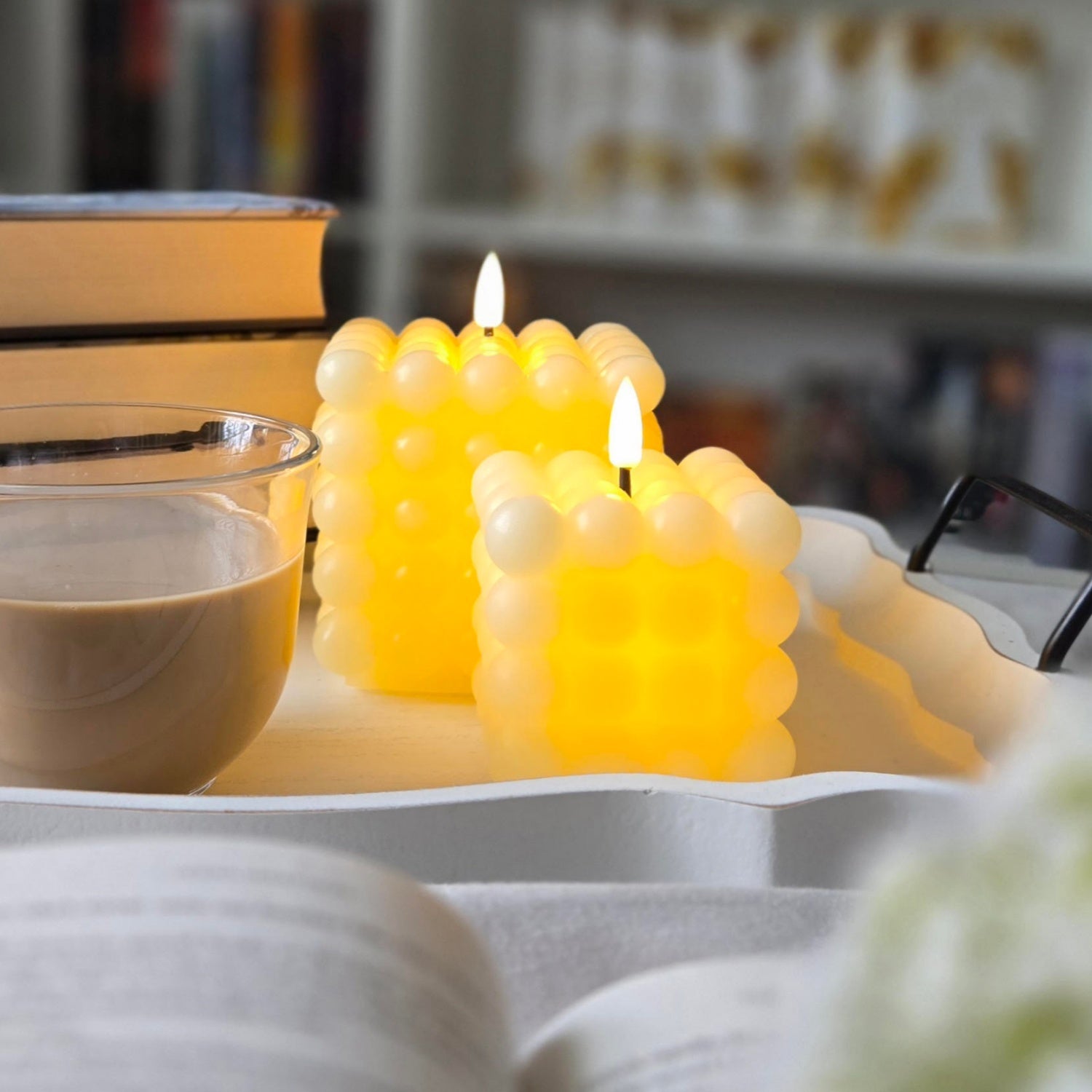 Two lit candles with a bubble design on a table, with a blurred background.