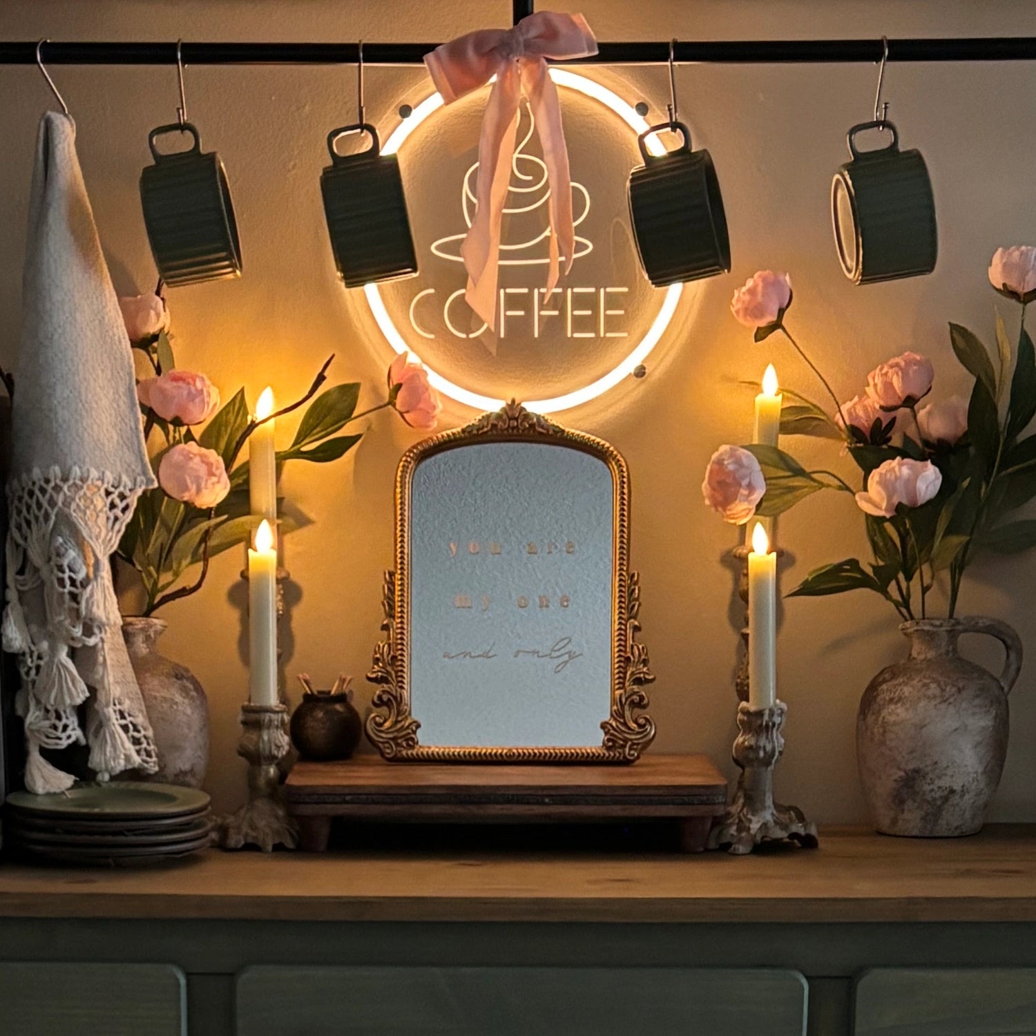 Decorative setup with a mirror, candles, flowers, and a 'Coffee' sign in a warm setting.