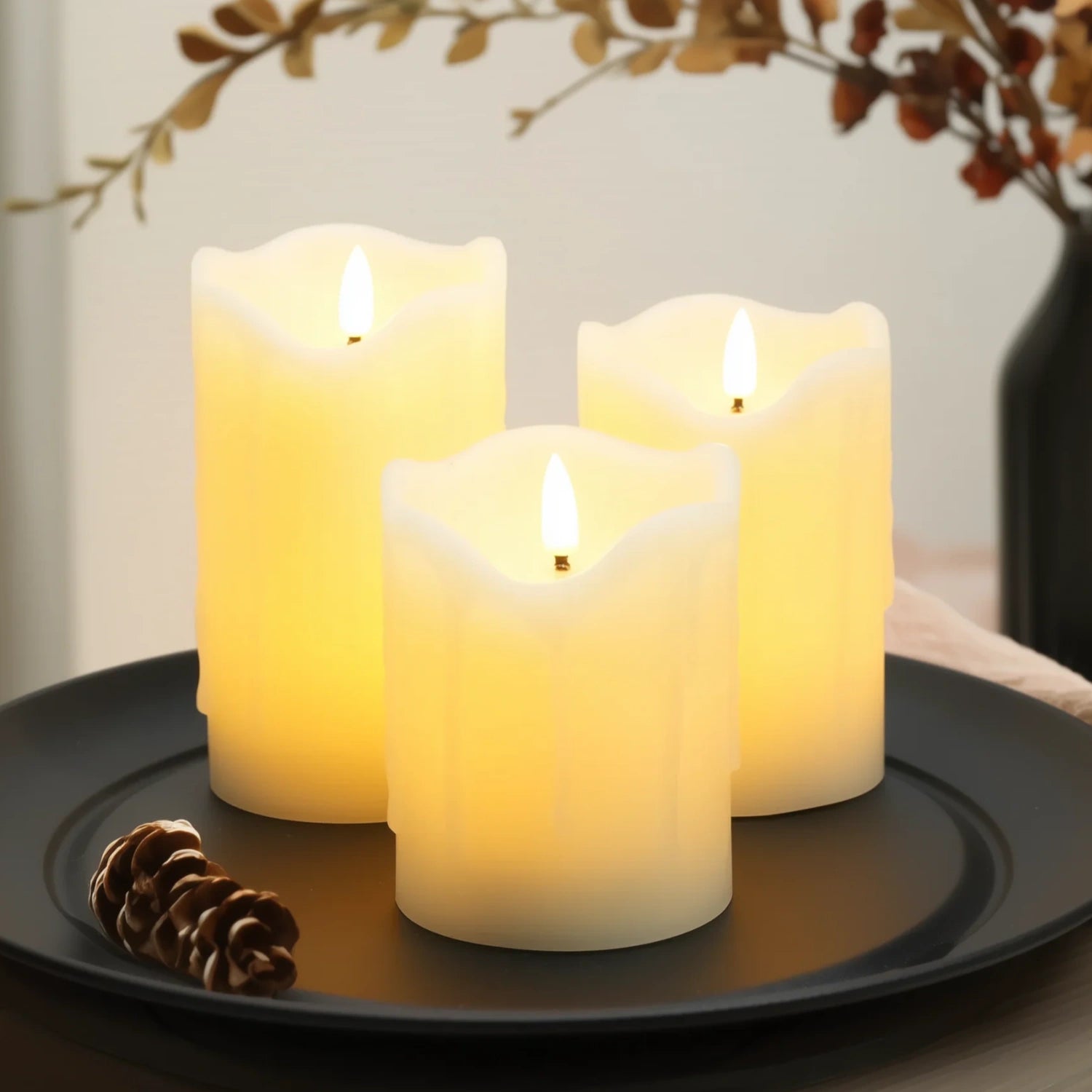 Three lit candles on a dark plate with decorative elements