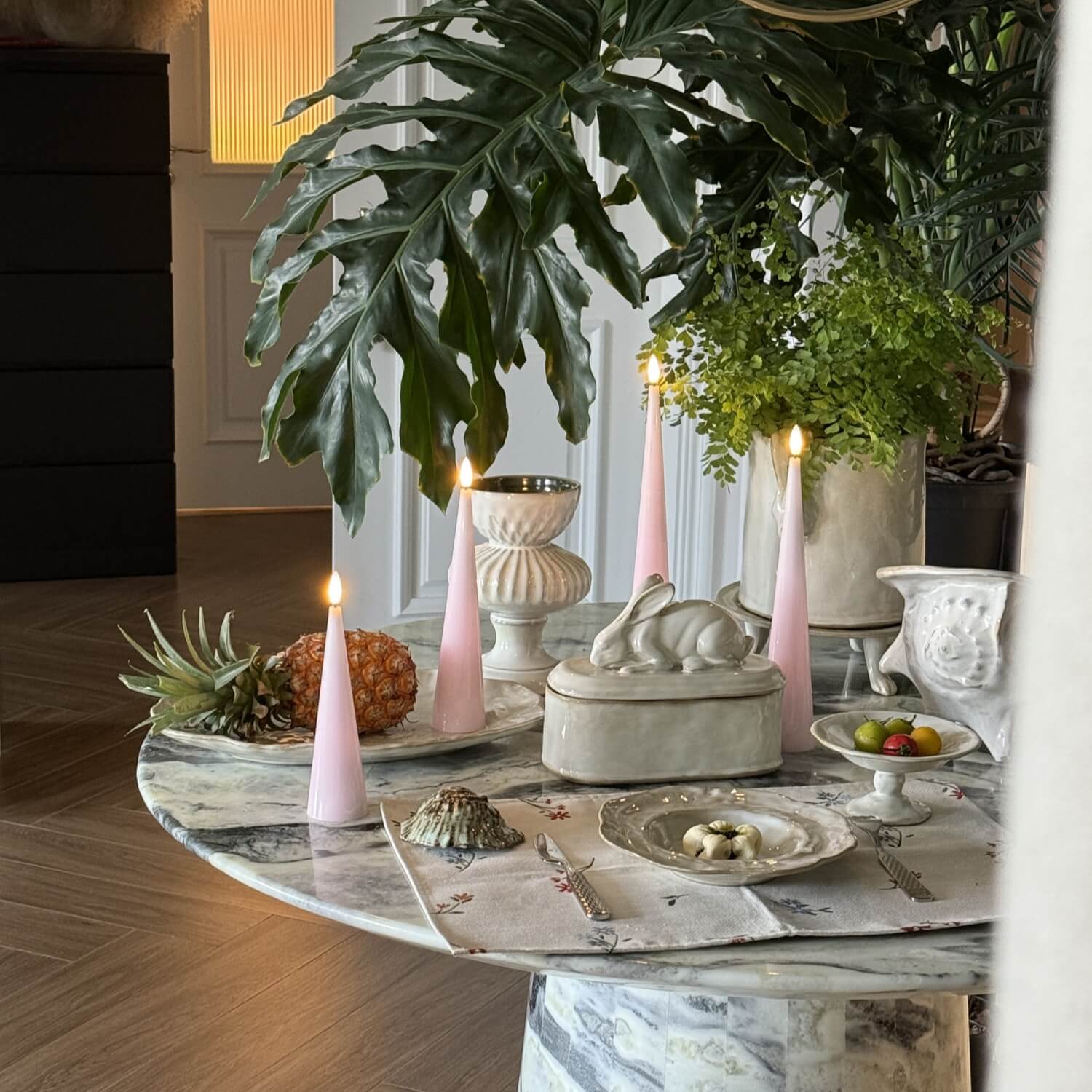Decorative table setting with candles, fruit, and decorative items on a marble table.