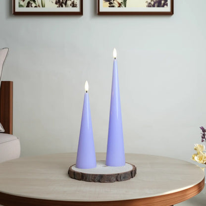 Two purple cone-shaped candles on a wooden base with a neutral background