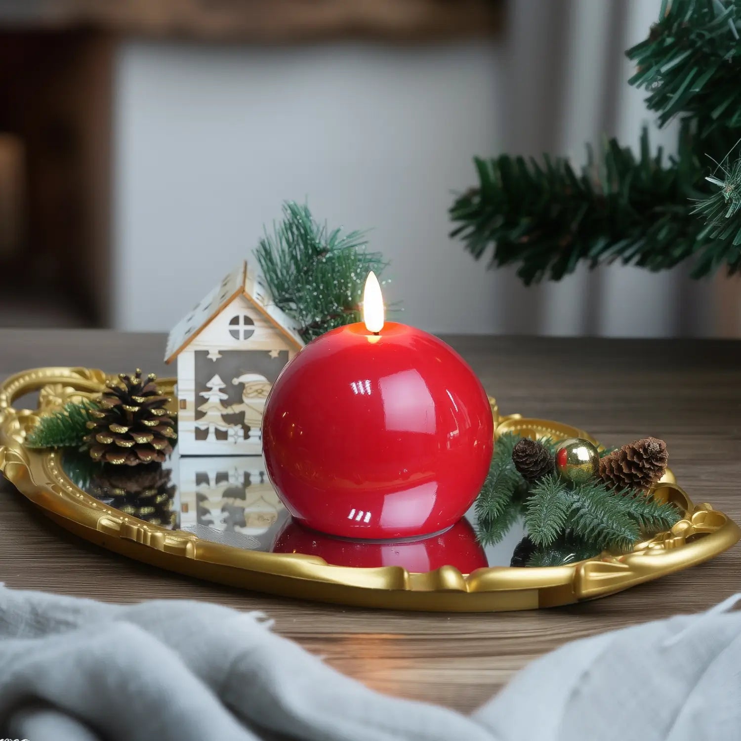 Red candle on a wooden tray with Christmas decorations on a table.#color_shiny-red
