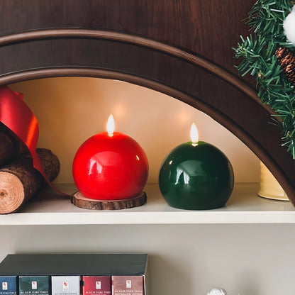Red candle on a wooden tray with Christmas decorations on a table.