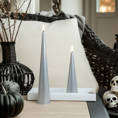 Two silver candles on a white base with decorative elements including pumpkins and skulls.