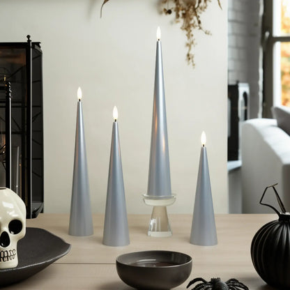 Set of silver cone-shaped candles on a table with decorative items.