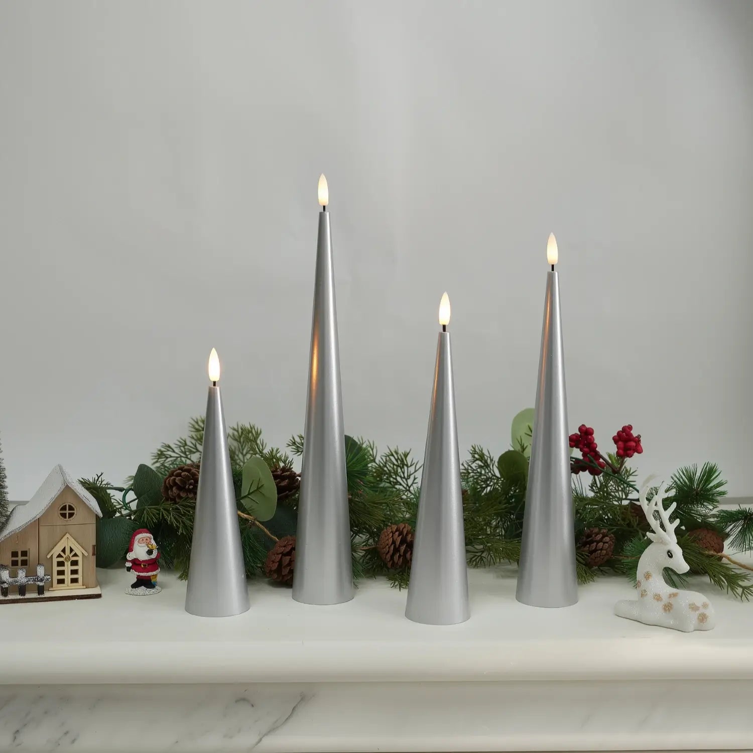 Set of four gray cone-shaped candles on a table with a fireplace and Christmas decorations in the background.